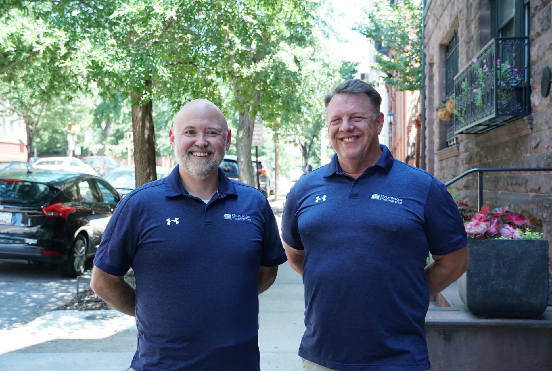 Dominion Properties team members Brian and Darren standing together on a tree-lined Baltimore street