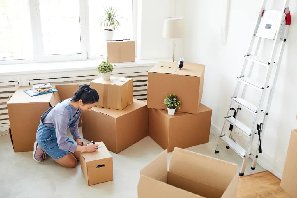 Woman packing boxes for a move in the living room.