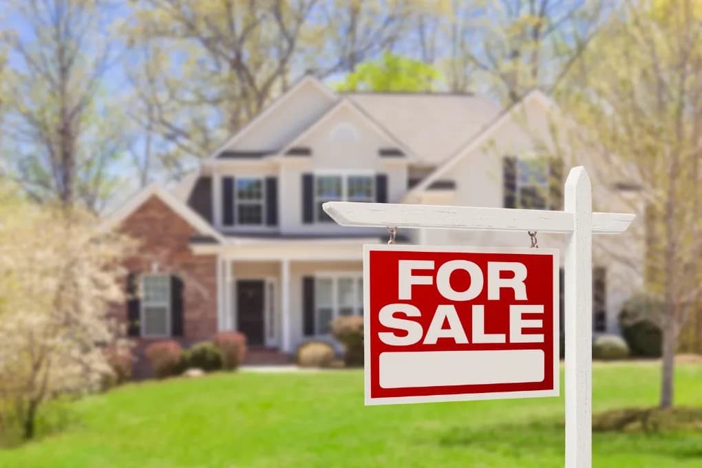 White, large house with for sale sign in the front yard.