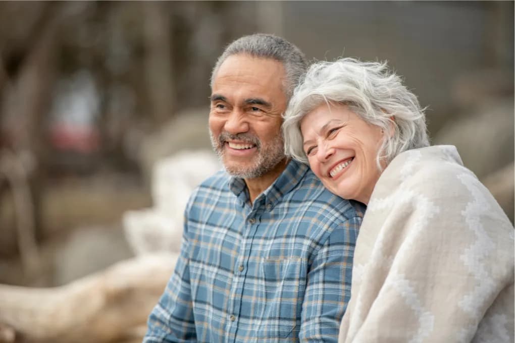 Elderly man and woman sitting together, smiling.