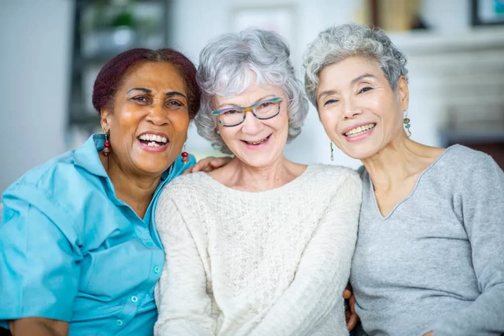Three older women smiling together.