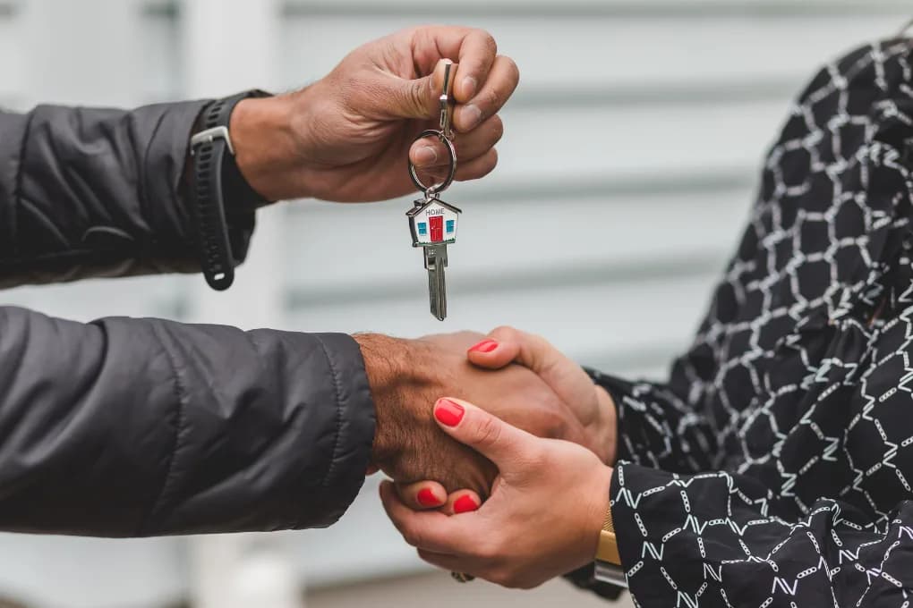 Man giving keys to woman, close up photo of their hands.