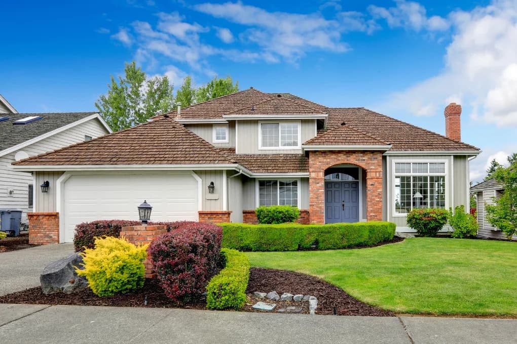 Street-view of home with neatly trimmed bushes in the front yard.