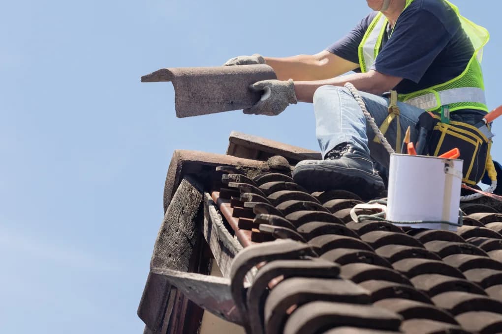 Worker sitting on roof, and repairing the roof.