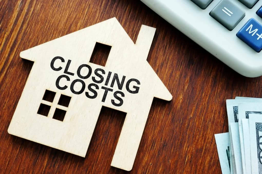 House figurine on table with text on it saying "closing costs."