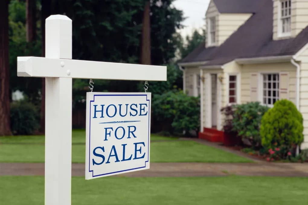House with a "house for sale" sign on the front yard.