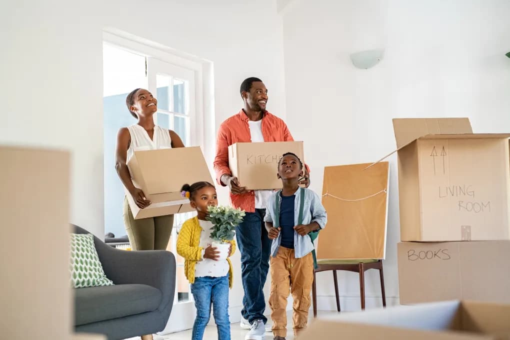 Family moving into a new home carrying boxes.